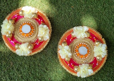 Floral Art presents Two decorative items with intricate designs, featuring white flowers and an orange-centered arrangement, placed on a grass surface. Perfect as flower jewelry for a bride or floral bridal jewellery for special occasions.