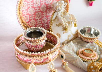 Floral Art presents Discover our decorative Indian thali set, featuring intricate beadwork and bowls, all elegantly arranged on a textured cloth bag with tassels against a patterned background. Perfect for showcasing alongside floral jewellery or as an accessory for a flower jewelry-loving bride.