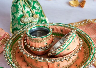 Floral Art presents A decorative display of peach and green bangles in ornate containers with a green drawstring pouch is set against a vibrant floral bridal jewellery background, perfect for complementing the festivities.