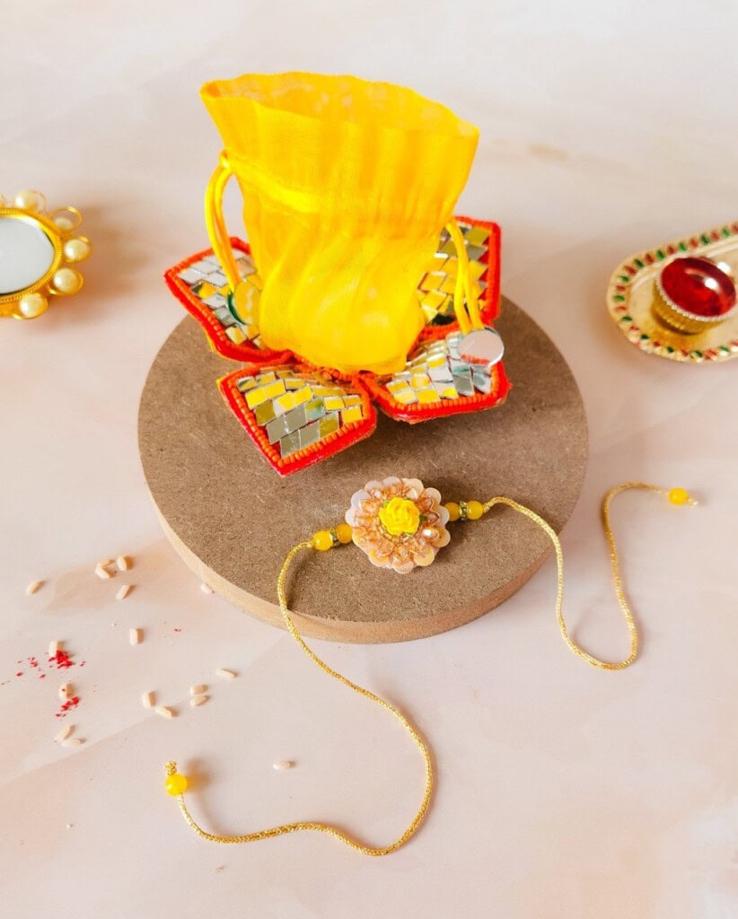Floral Art presents A decorative craft featuring a yellow vase, a floral wristband, and colorful embellishments on a circular platform.