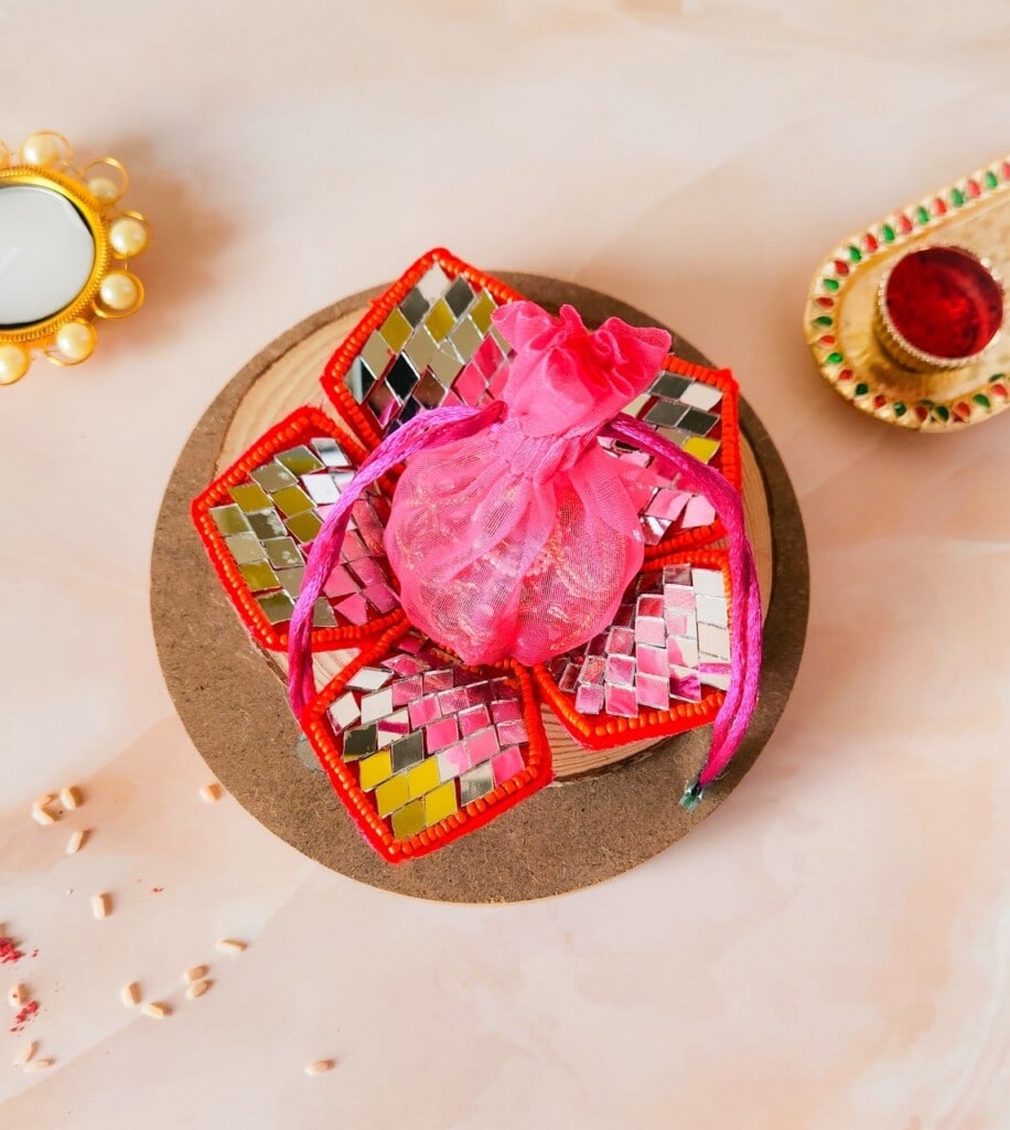 Floral Art presents A decorative tray with colorful mosaic tiles holds a pink drawstring pouch. Various decorative items are placed around the tray.