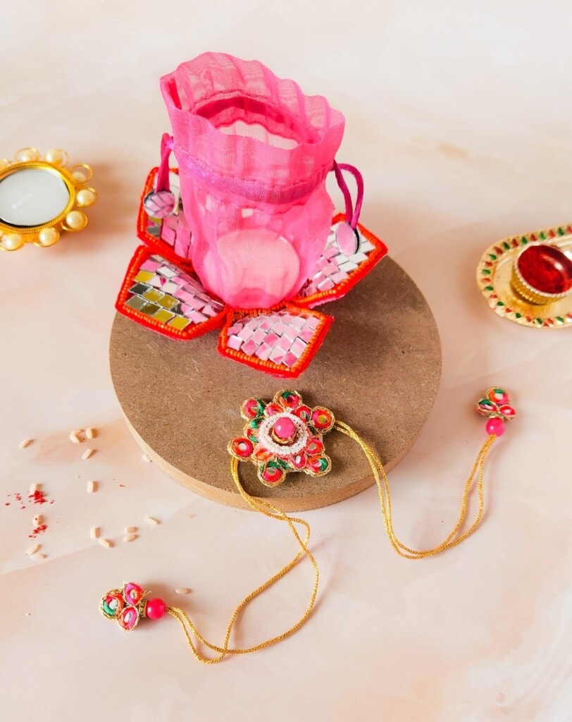 Floral Art presents A pink velvet pouch with traditional jewelry, including a necklace and rings, displayed on a round platform, surrounded by decorative items on a light surface.