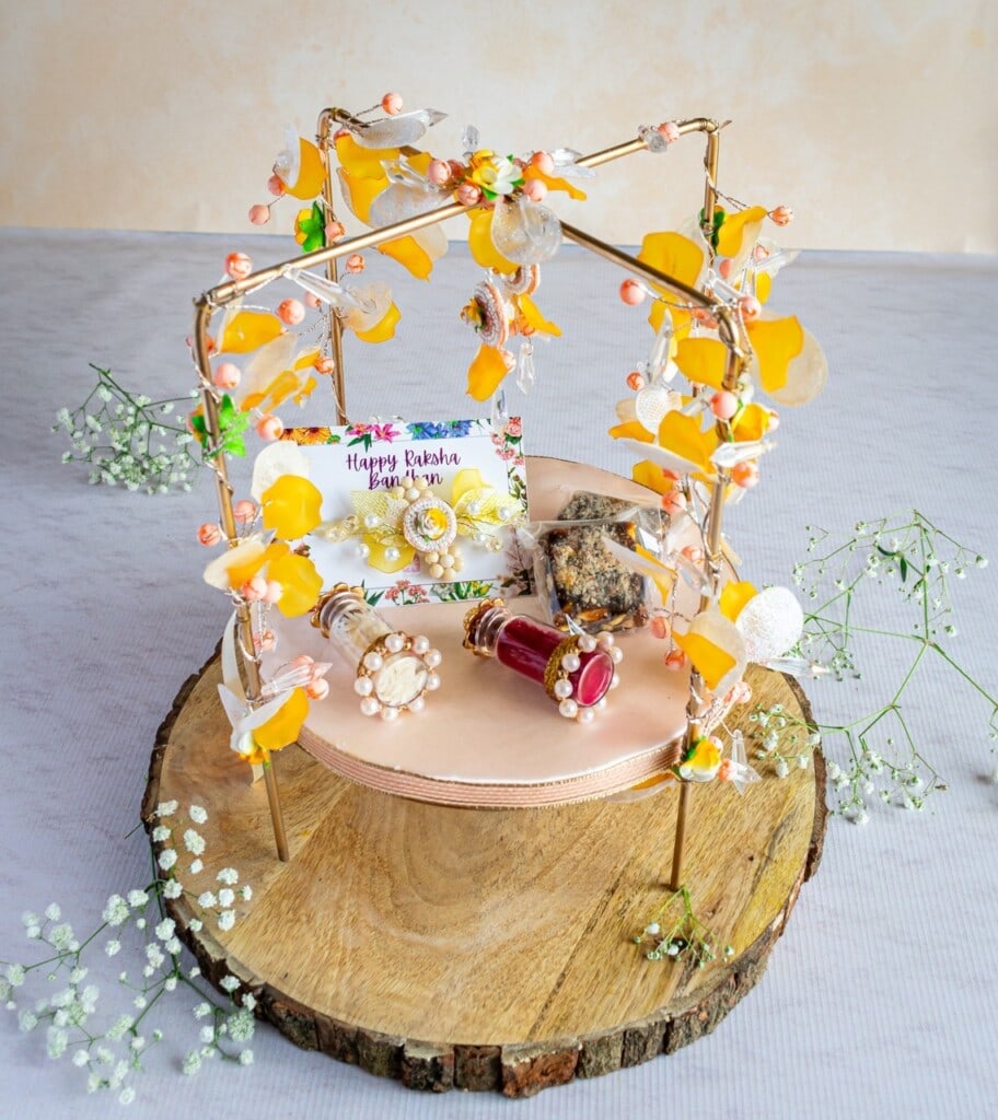 Floral Art presents A decorative tray holds assorted beauty products, jewelry, and a Happy Birthday card, all surrounded by yellow flowers and baby's breath on a wooden base.