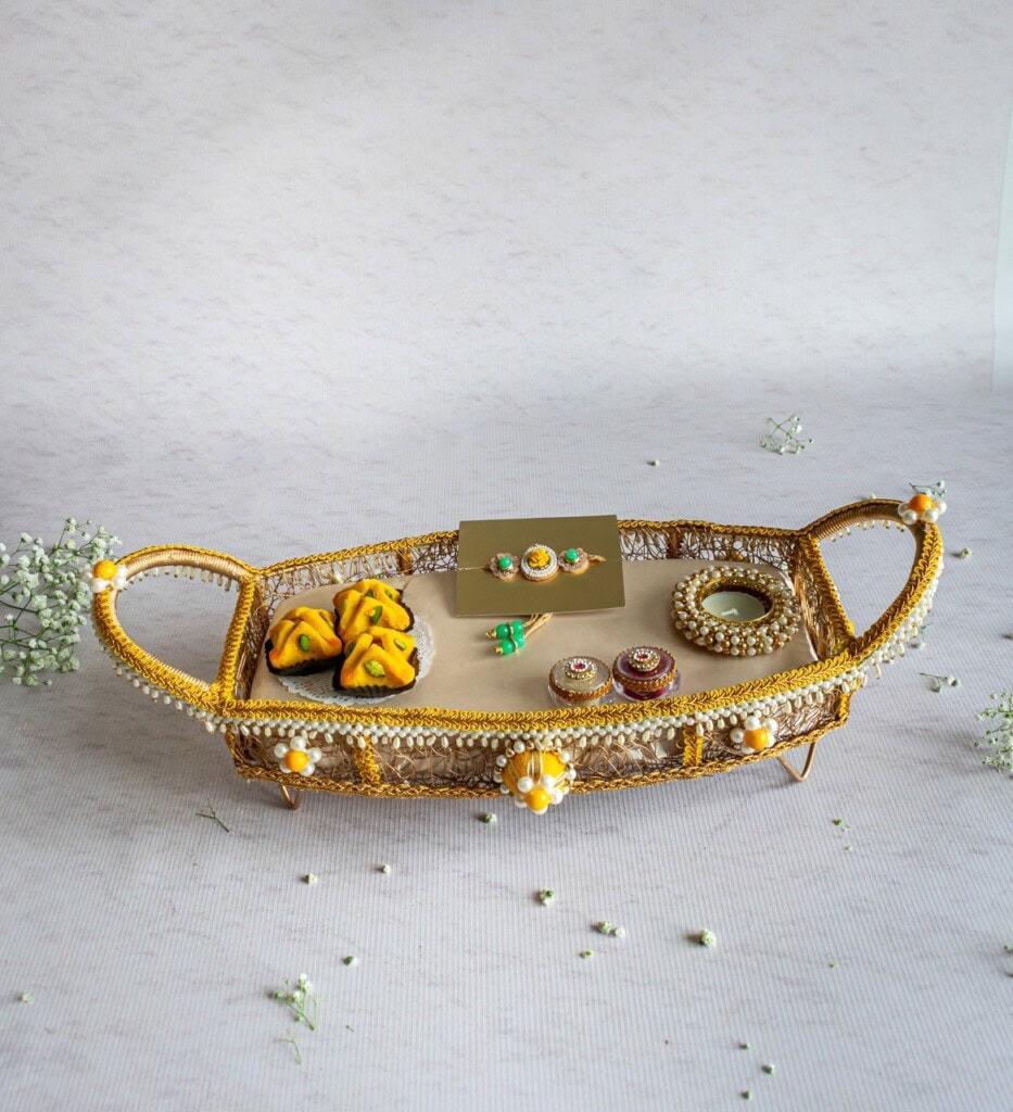 Floral Art presents A decorative tray holds traditional items including sweets, jewelry, and a small mirror, arranged on a mesh surface with pearl accents.