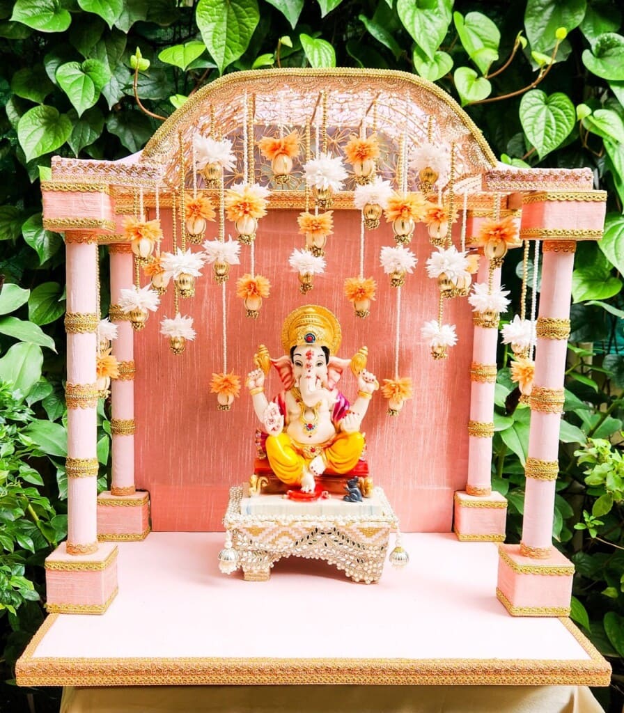 Floral Art presents Statue of Lord Ganesha on a decorated pedestal with hanging flowers and a foliage background.