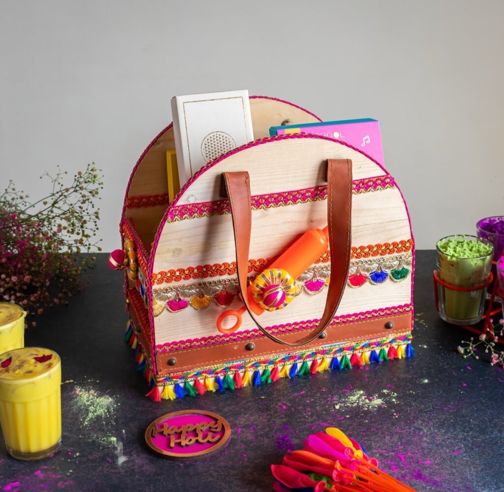 Floral Art presents Colorful decorative basket with flowers, candles, powder, and drinks, set on a table.
