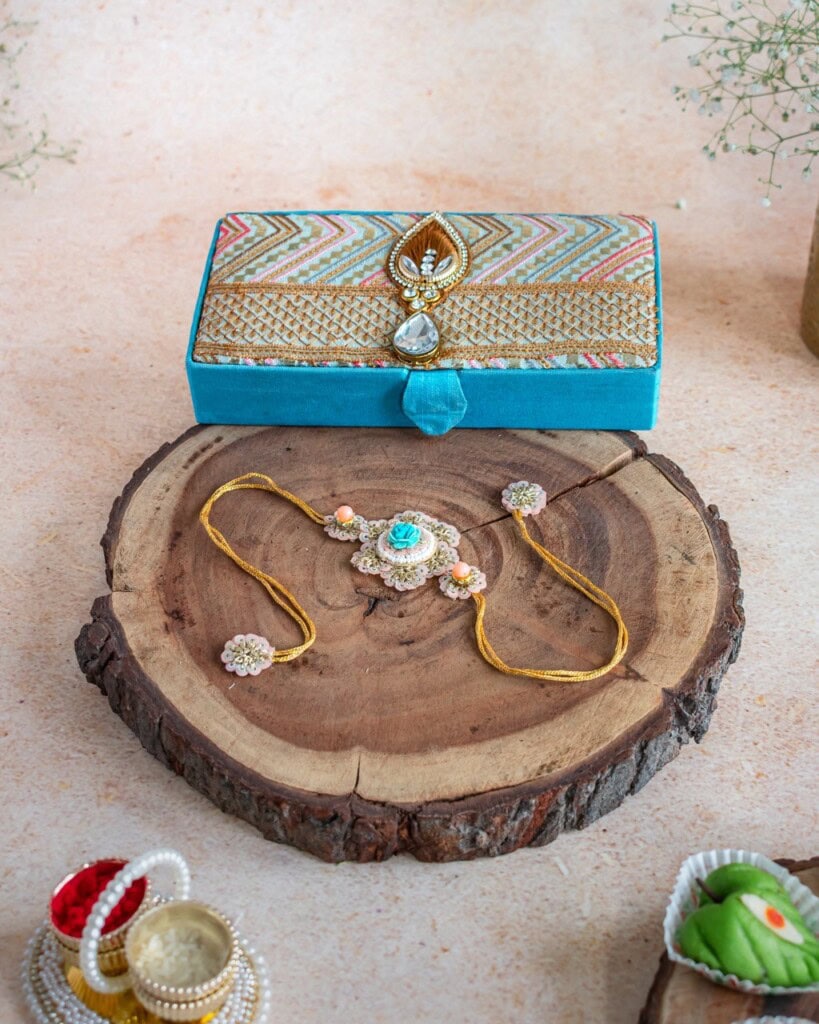 Floral Art presents A decorative jewelry box and an embellished bracelet are displayed on a wooden slab, with small bowls of traditional items nearby.