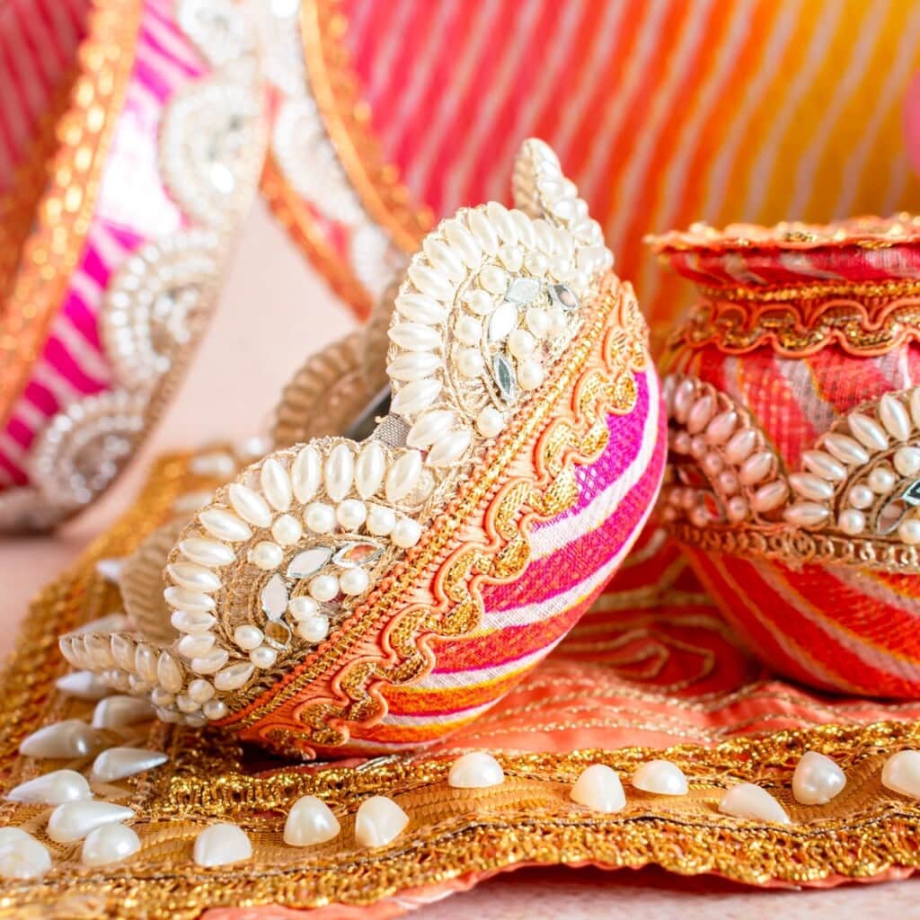 Floral Art presents Decorative Indian bangles and containers adorned with pearls and gold embroidery, set on a matching ornate tray with vibrant pink and orange patterns.