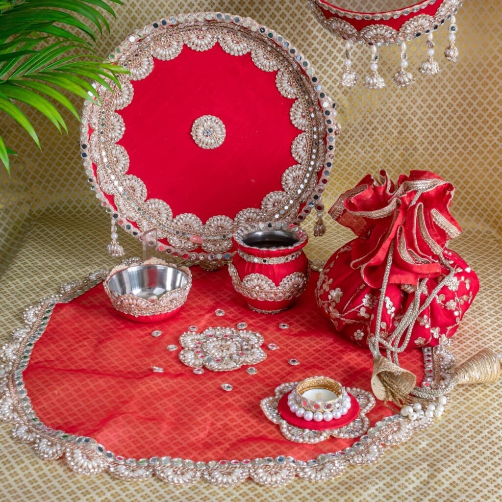 Floral Art presents A traditional red and silver decorated pooja thali set with bowls, kalash, diya, pouch, and accessories arranged on a matching mat.
